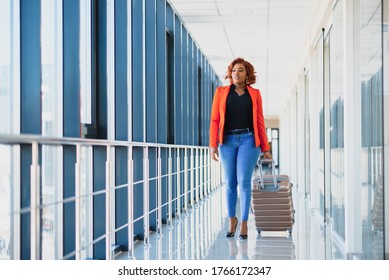 Full Length Side Portrait Of Young Black Woman Walking With Suitcase In Airport