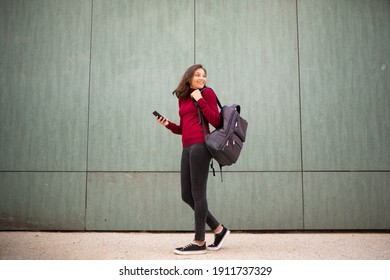 Full Length Side Portrait Young Woman Walking With Bag And Mobile Phone By Wall