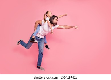 Full length side profile body size photo she her little lady he him his daddy dad hold little princess piggyback hands arms ready fly wear casual white t-shirts denim jeans isolated pink background