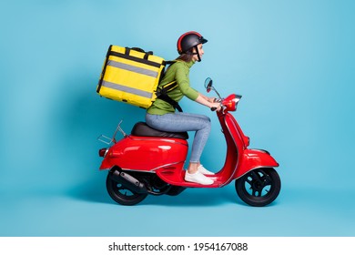 Full length side profile photo portrait of woman delivering big yellow package on red scooter isolated on pastel blue colored background - Shutterstock ID 1954167088