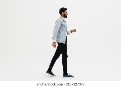 Full length side shot of handsome beard man walking, isolated on white background