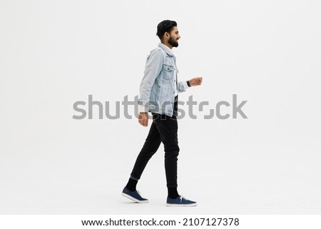 Full length side shot of handsome beard man walking, isolated on white background