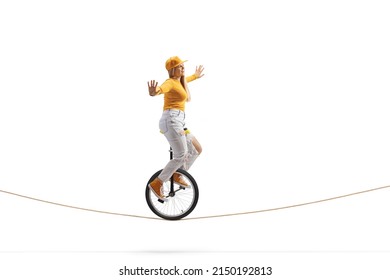 Full length side shot of a young female riding a unicycle on a tightrope isolated on white background - Powered by Shutterstock