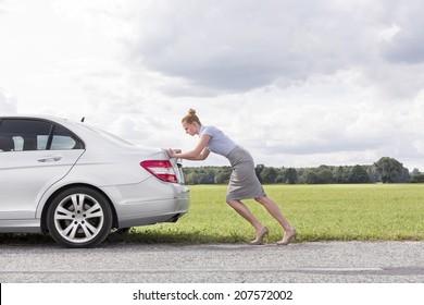 Full Length Side View Of Businesswoman Pushing Broken Down Car At Countryside