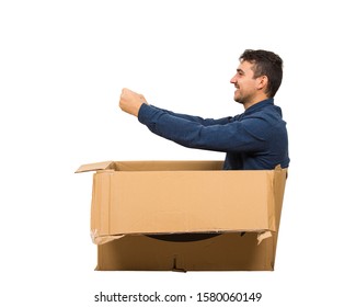 Full Length Side View Of Childish Man Sitting Inside A Cardboard Box Pretending To Drive A New Car Isolated Over White Background. Joyful Guy Dreaming Of Buying A Personal Vehicle.