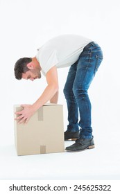 Full length side view of delivery man picking cardboard box on white background