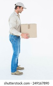 Full length side view of delivery man carrying cardboard box against white background