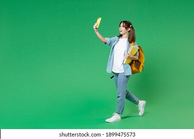 Full length side view of excited woman student in shirt backpack hold notebooks doing selfie shot on mobile phone isolated on green background. Education in high school university college concept - Shutterstock ID 1899475573