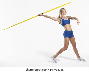 Full length side view of a female athlete preparing to throw javelin against white background - Powered by Shutterstock