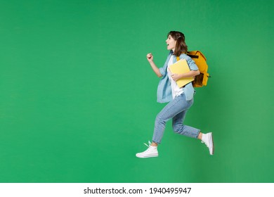 Full Length Side View Funny Young Woman Student In Shirt Backpack Hold Notebooks Jumping Like Running Isolated On Green Background Studio Portrait. Education In High School University College Concept