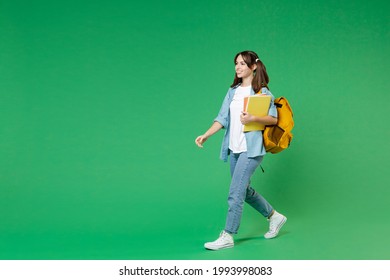 Full Length Side View Of Funny Young Woman Student In Blue Shirt Backpack Hold Notebooks Walking Going Isolated On Green Color Background Studio. Education In High School University College Concept