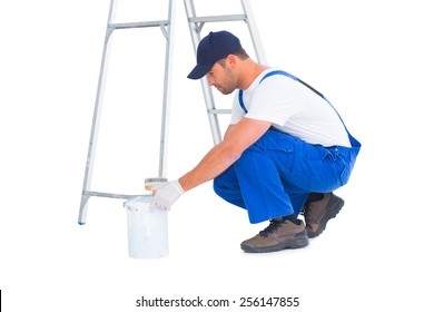 Full length side view of handyman with paint can on white background