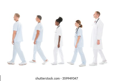 Full Length Side View Of Medical Team Walking In Row Against White Background