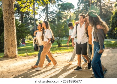 Full length side view of multiracial young friends walking together along a sandy path at park