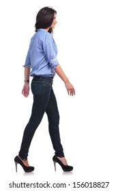 Full Length Side View Picture Of Young Casual Woman Walking In Front Of The Camera While Looking Forward. On White Background