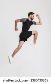 Full length side view portrait of a confident young sportsman jumping isolated over white background - Shutterstock ID 1380430865