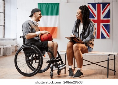 Full length side view portrait of smiling young sportsman with disability giving interview to girl holding clipboard copy space - Powered by Shutterstock