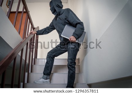 Full length side view of robber stealing laptop from office at night