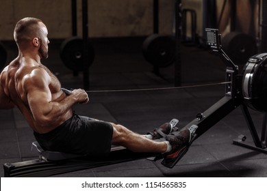 Full Length Side View Shot. A Fit Young Man Working Out With A Indoor Rower. Lifestyle And Hobby Concept