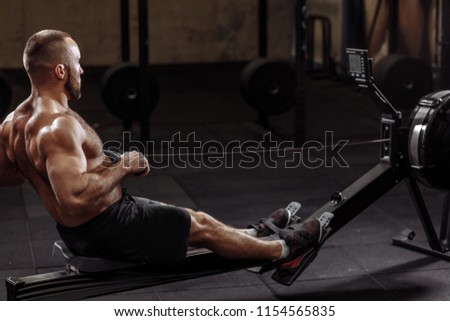 full length side view shot. a fit young man working out with a indoor rower. lifestyle and hobby concept