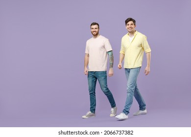 Full Length Side View Two Young Happy Men 20s Friends Together Wear Casual T-shirt Walking Going Strolling Lokk Camera Isolated On Purple Background Studio Portrait People Friendship Lifestyle Concept