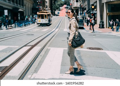 Full Length Side View Of Young Pretty Stylish Asian Chinese Female Crossing Zebra Road Of San Francisco Usa. Historic Cable Cars Riding On Famous California Street At Dawn On Sunny Day In Busy Urban