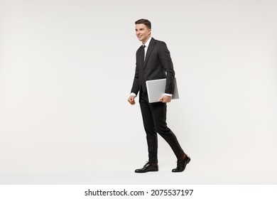 Full Length Side View Young Employee Business Corporate Lawyer Man Wearing Classic Formal Black Grey Suit Shirt Tie Work In Office Hold Closed Laptop Computer Walk Isolated On White Background Studio