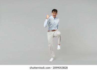 Full Length Side View Young Happy Successful Employee Business Latin Man Corporate Lawyer In Classic White Shirt Glasses Walk Do Winner Gesture With Raised Up Leg Isolated On Grey Background Studio