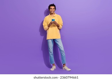 Full length size body photo of optimistic man student chatting online youth guy hold samsung phone isolated on violet color background