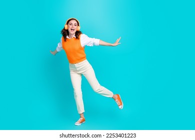 Full length size photo of overjoyed careless schoolgirl listen soundtrack loud music headphones dance crazy isolated on aquamarine color background