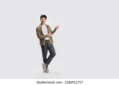 Full length smart young Asian man happy smile standing hand pointing to empty space on white background. Short on studio. - Shutterstock ID 2186911757