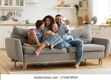Full length smiling father holding cellphone, making selfie shot, recording video with happy wife and little kids siblings. Excited parents looking at mobile screen with kids, feeling excited.