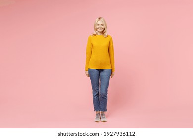 Full Length Of Smiling Pretty Elderly Gray-haired Blonde Woman Lady 40s 50s Years Old Wearing Yellow Basic Sweater Standing And Looking Camera Isolated On Pastel Pink Color Background Studio Portrait