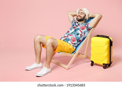 Full length of smiling young traveler tourist man in summer clothes hat sit on deck chair hold hands behind head isolated on pink background. Passenger travel on weekend. Air flight journey concept - Powered by Shutterstock