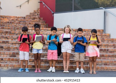 Full length of students using digital tablets outside school