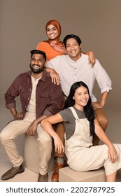 Full Length Studio Portrait Of Four People From Diverse Ethnic Backgrounds Posed Smiling On A Neutral Background