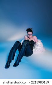 Full Length Of Stylish Woman In White Faux Fur Jacket And Black Leather Pants Posing On Blue Background