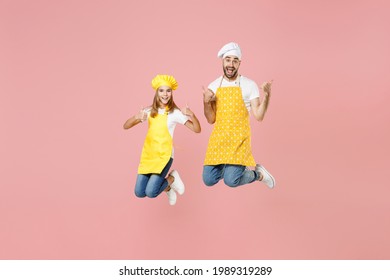 Full Length Teen Overjoyed Girl Dad Father's Helper Chef Cook Confectioner Baker In Yellow Apron Cap Jump High Show Thumb Up Like Gesture Celebrate Isolated On Pastel Pink Background Studio Portrait