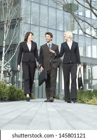 Full Length Of Three Business People Walking Outside Office Building