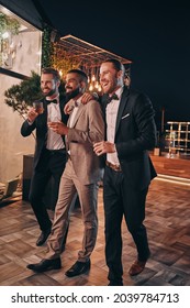Full length of three handsome men in suits and bowties drinking whiskey and communicating - Shutterstock ID 2039784713