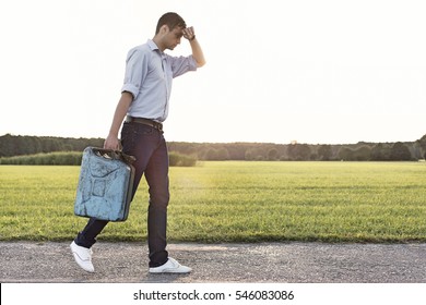 Full Length Of Tired Young Man With Gas Can Walking On Rural Road