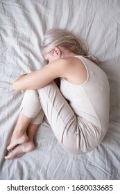 Full Length Top Above View Stressed Middle Aged Woman Lying On Bed In Fetal Position, Embracing Knees, Suffering From Depression Or Insomnia. Upset Mature Lady Feeling Unwell, Having Health Problems.