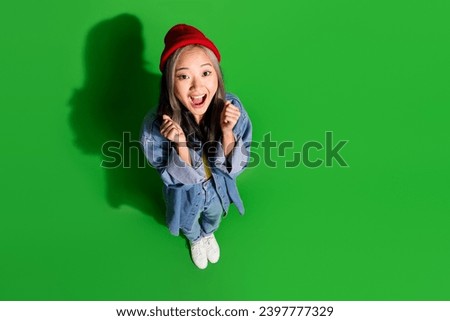Full length top view photo of lucky excited lady wear denim jacket rising fists empty space isolated green color background