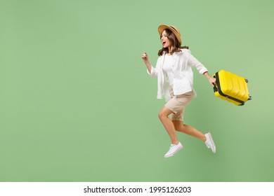 Viajera de largo recorrido mujer turista con ropa informal que salta alto sostiene maleta que corre aislado en un fondo verde pastel. Los pasajeros viajan al extranjero los fines de semana escapando. concepto de viaje aéreo