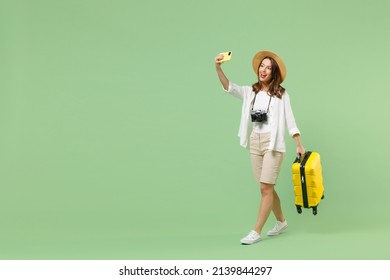 Full length traveler tourist woman in casual clothes hat hold suitcase do selfie on mobile cell phone isolated on pastel green background. Passenger travel abroad weekends. Air flight journey concept - Shutterstock ID 2139844297