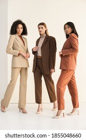full length of trendy interracial models in suits posing on white - Shutterstock ID 1855048660