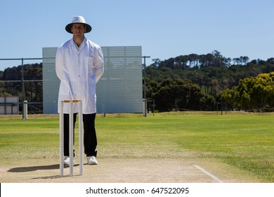 Full length of umpire standing behind stumps during cricket match on sunny day - Powered by Shutterstock