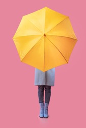 Full Length Of Unrecognizable Model In Autumn Clothes Hiding Behind Yellow Umbrella, Vertical Studio Shot