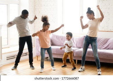 Full Length View Active African Ethnicity Couple And Their Kids Daughter And Son Dancing Standing In Modern Living Room, Homeowners Enjoy Free Time Together Listen Music Spend Funny Activities At Home