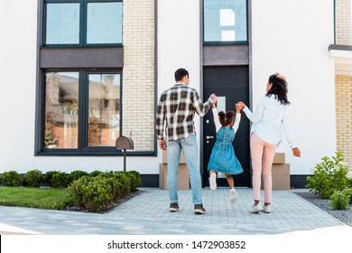 Full Length View Of African American Couple Holding Hands With Kid And Walking To New House 